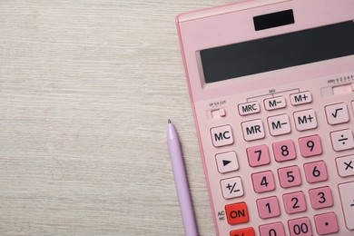 Calculator and pen on light wooden table, top view. Space for text