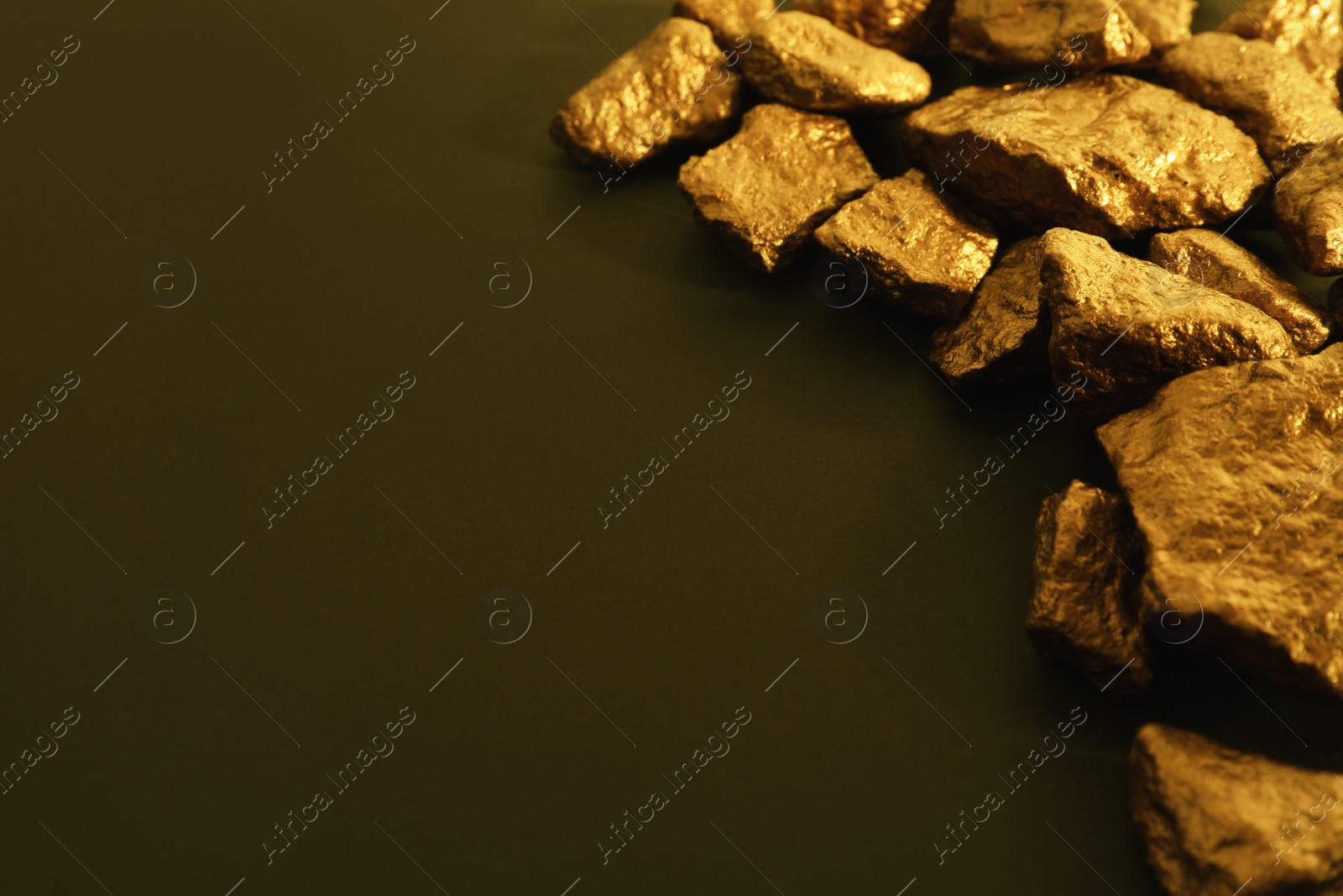 Photo of Pile of gold nuggets on color background. Space for text