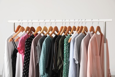 Wardrobe rack with stylish clothes near white wall indoors