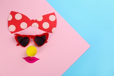 Flat lay composition with clown's face made of sunglasses and bow on color background. Space for text