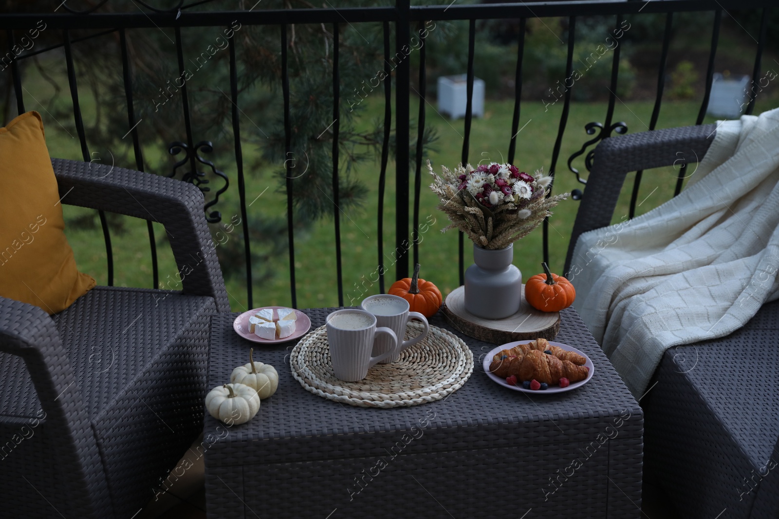 Photo of Rest on terrace with rattan furniture. Drink, dessert and autumn decor on table