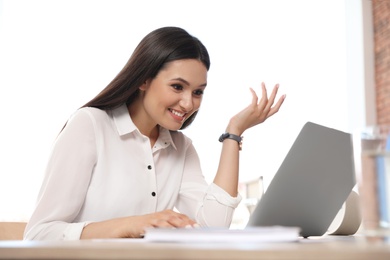 Young woman using video chat on laptop in home office