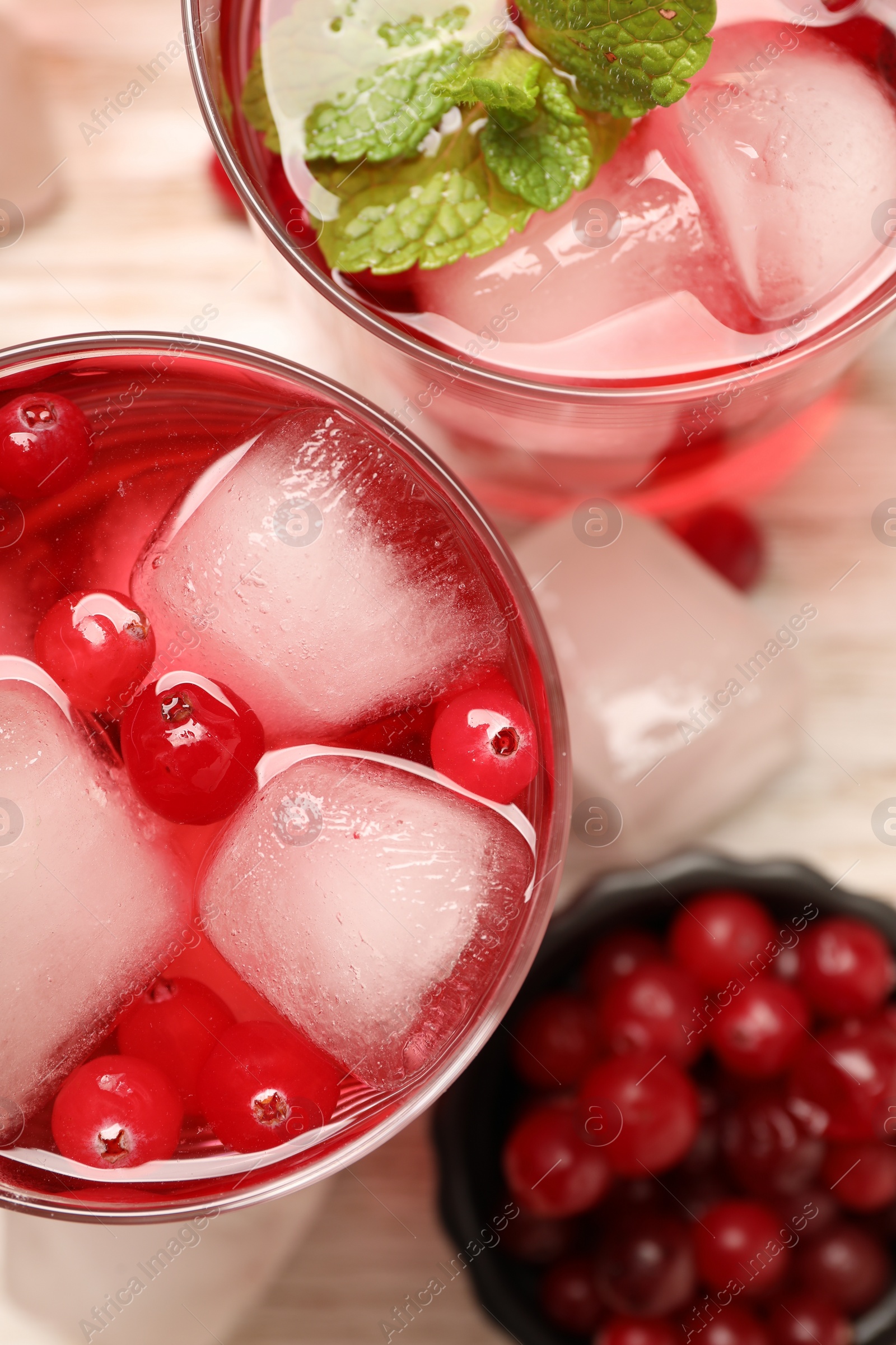 Photo of Tasty cranberry cocktail with ice cubes and mint in glasses on table, flat lay