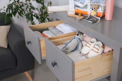 Photo of Open drawers of chest with baby stuff in room