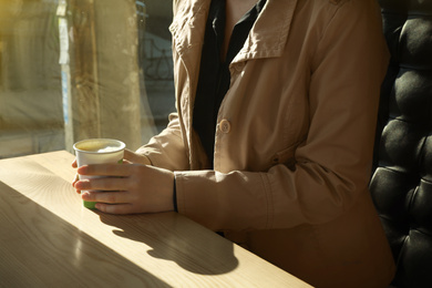 Photo of Woman with cup of fresh aromatic coffee at table in cafe