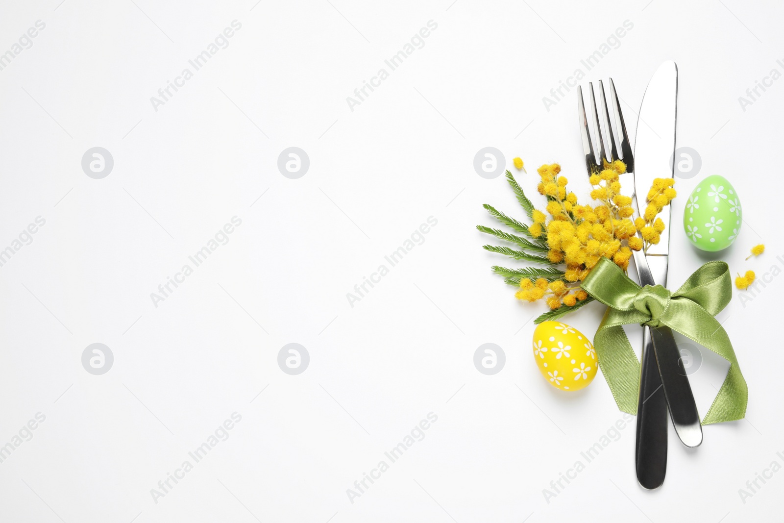 Photo of Top view of cutlery set with floral decor for Easter celebration on white background