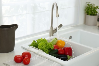 Many fresh ripe vegetables under tap water in kitchen sink