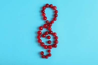 Photo of Treble clef made of cranberries on color background, top view. Musical notes