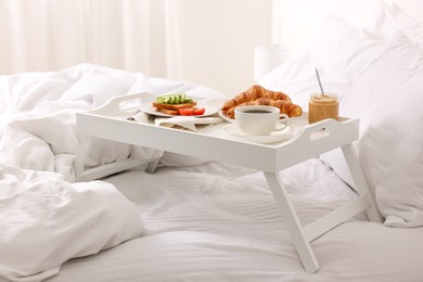 Photo of Good morning. Tray with tasty breakfast on bed at home