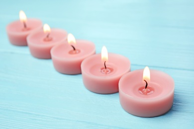 Burning decorative candles on light blue wooden table