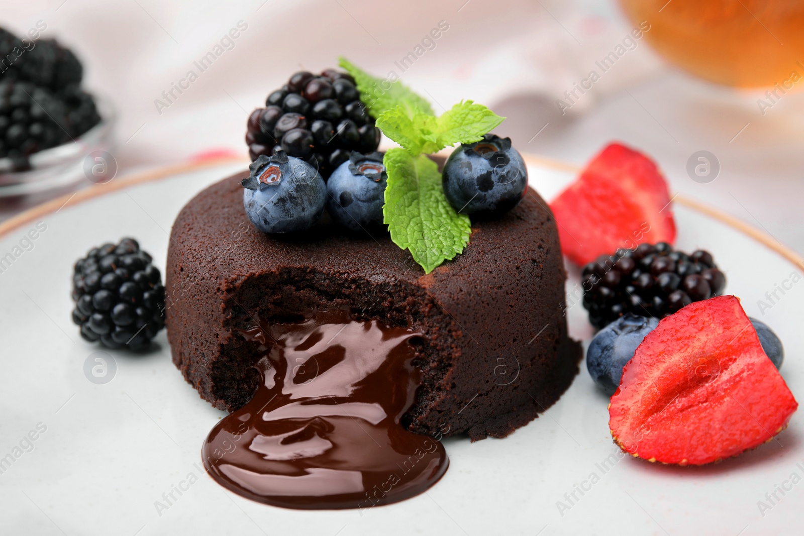 Photo of Delicious chocolate fondant, berries and mint on plate, closeup