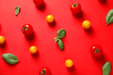 Flat lay composition with ripe cherry tomatoes and basil leaves on color background