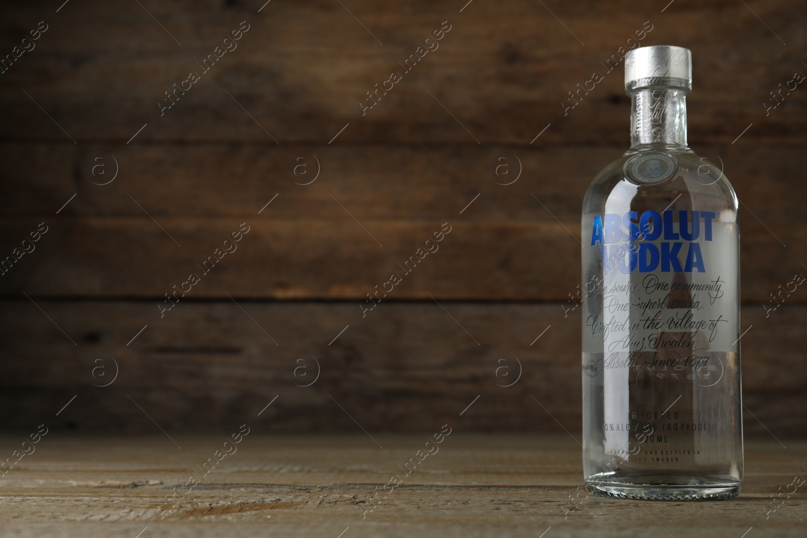 Photo of MYKOLAIV, UKRAINE - OCTOBER 03, 2019: Bottle of Absolut vodka on table against wooden background. Space for text