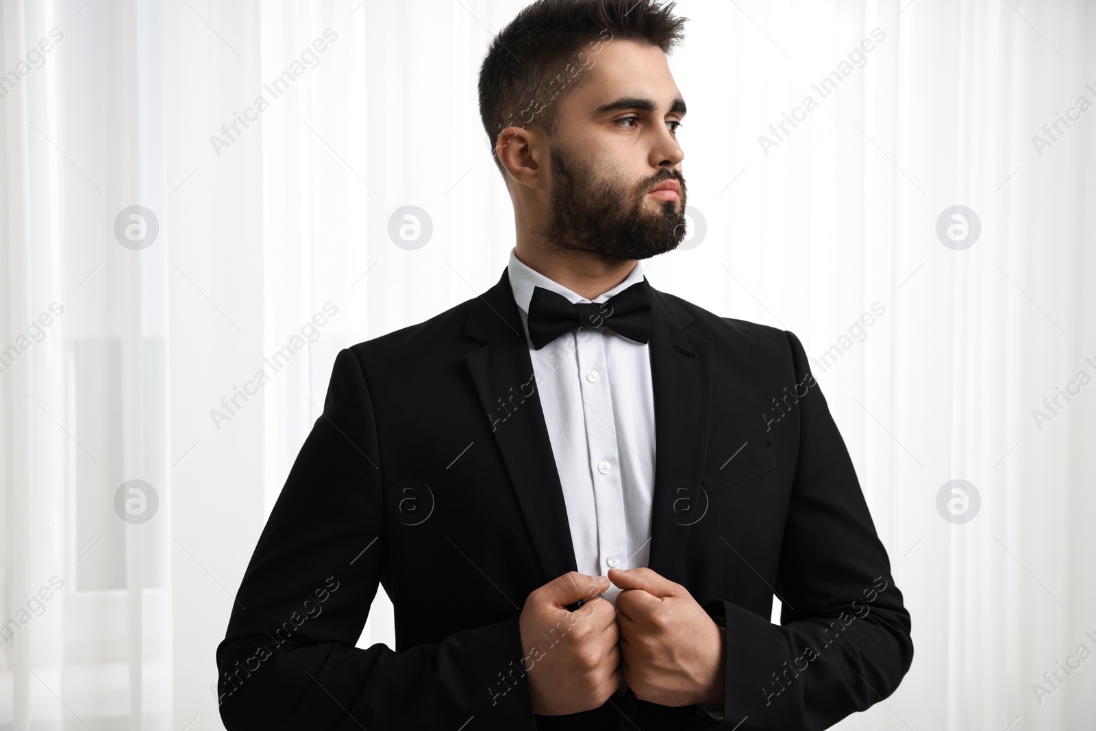 Photo of Portrait of handsome man in suit, shirt and bow tie indoors