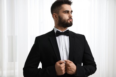 Photo of Portrait of handsome man in suit, shirt and bow tie indoors