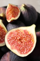 Photo of Whole and cut ripe figs on blurred background, closeup