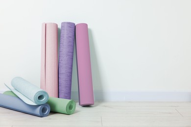 Colorful wallpaper rolls on light wooden floor in room. Space for text