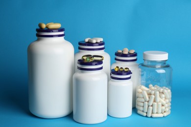 White medical bottles and different pills on light blue background