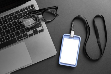 Photo of Blank badge, glasses and laptop on grey background, top view