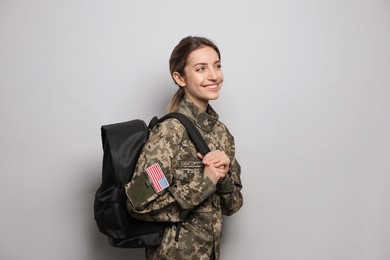 Photo of Female cadet with backpack on light grey background. Military education
