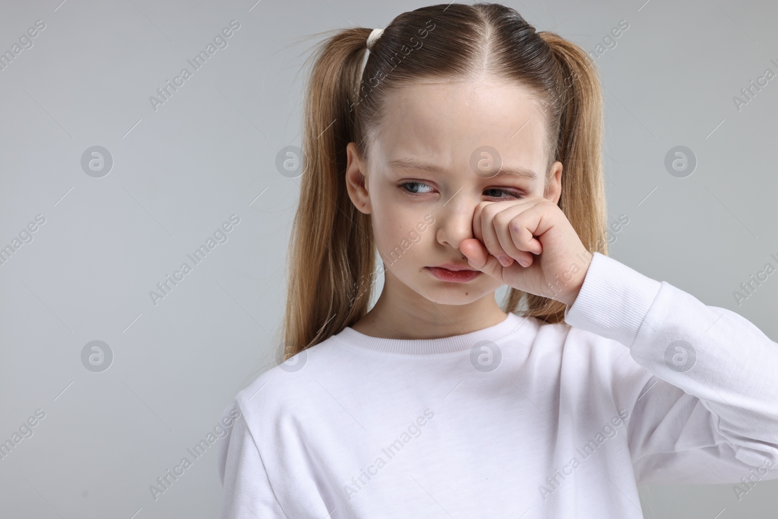 Photo of Portrait of sad girl on light grey background, space for text