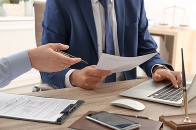 Photo of Lawyer working with client at table in office, focus on hands