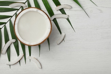 Photo of Flat lay composition with half of coconut on white wooden background. Space for text