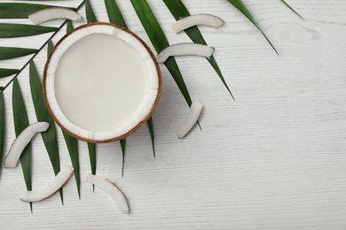 Flat lay composition with half of coconut on white wooden background. Space for text