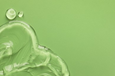 Clear cosmetic gel on light green background, top view. Space for text