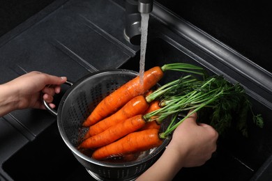 Photo of Woman washing fresh ripe juicy carrots under tap water in sink, above view