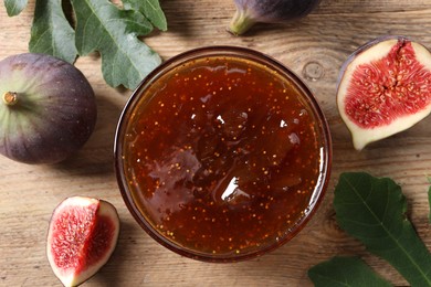 Bowl with tasty sweet jam and fresh figs on wooden table, flat lay