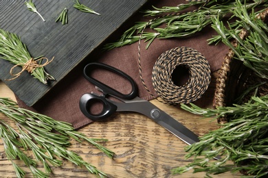 Flat lay composition with rosemary and scissors on wooden background. Aromatic herbs