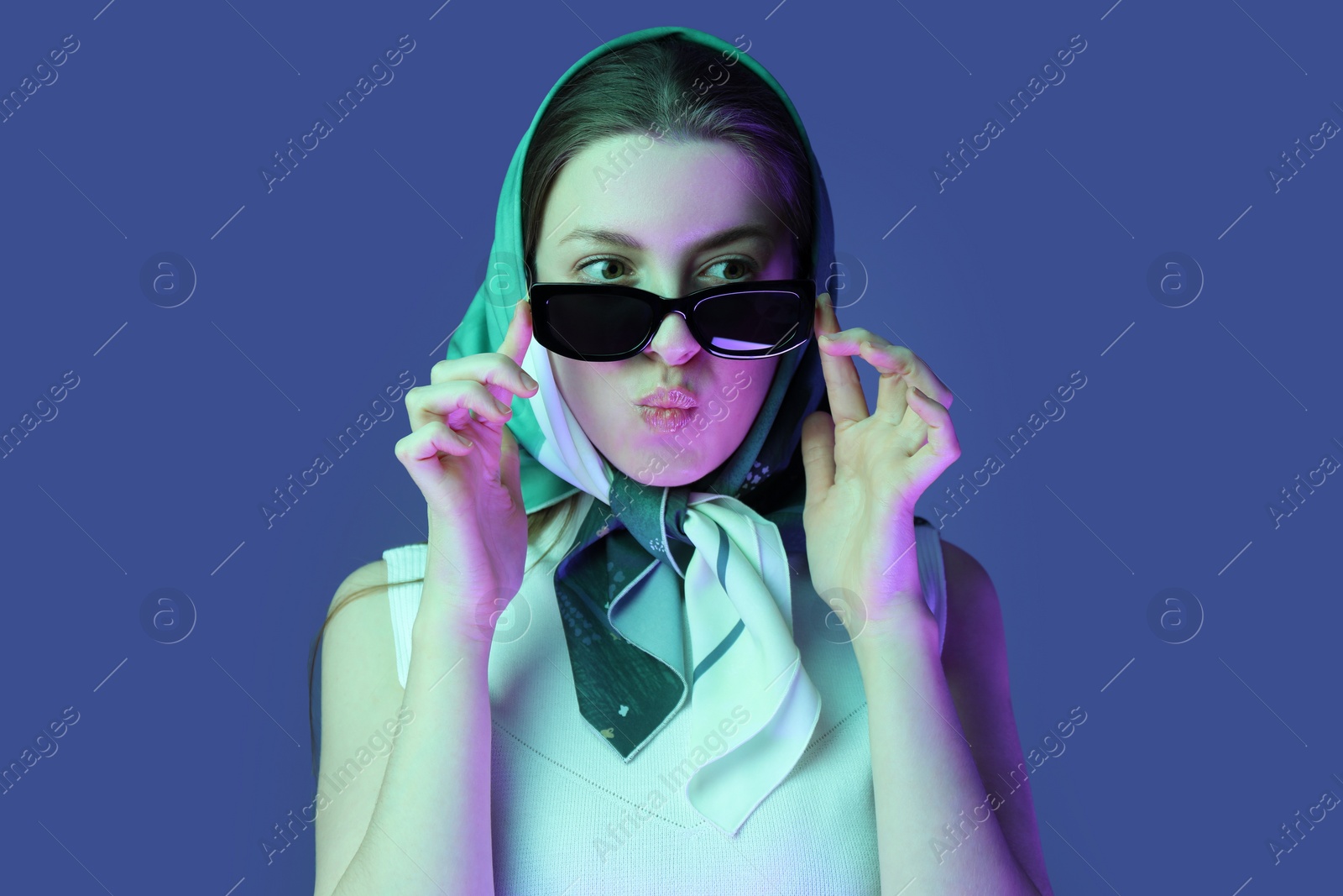 Photo of Portrait of beautiful young woman with sunglasses on color background with neon lights