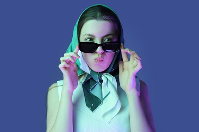 Portrait of beautiful young woman with sunglasses on color background with neon lights