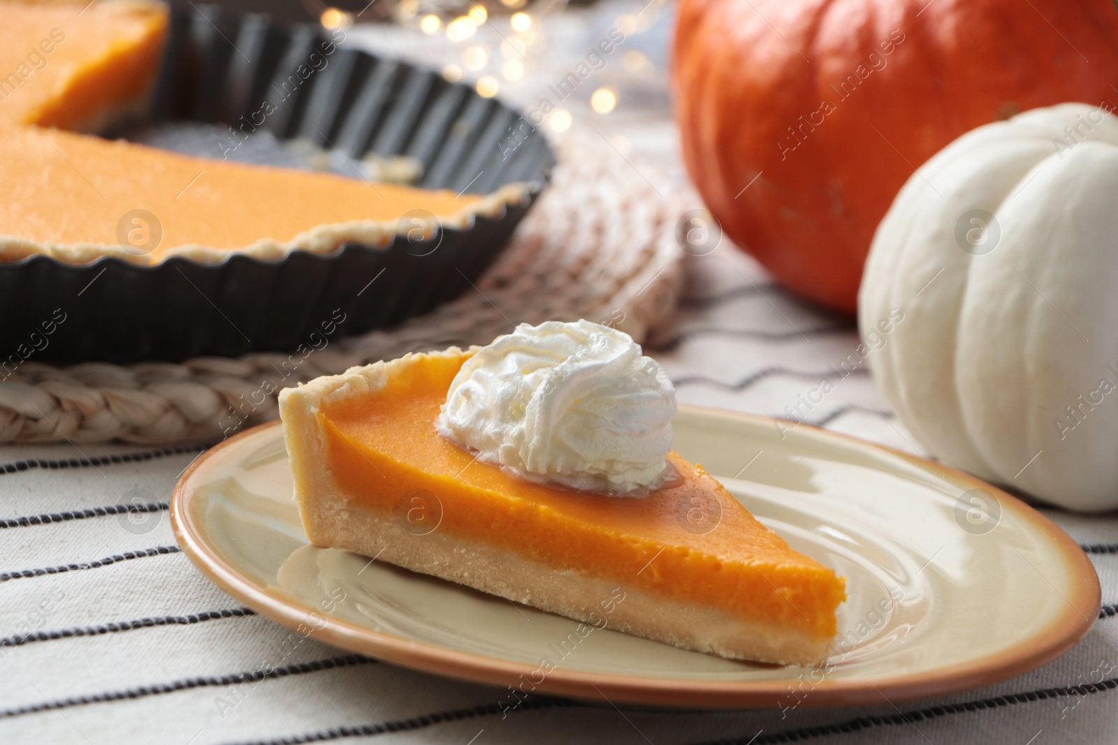 Photo of Piece of fresh homemade pumpkin pie with whipped cream on table