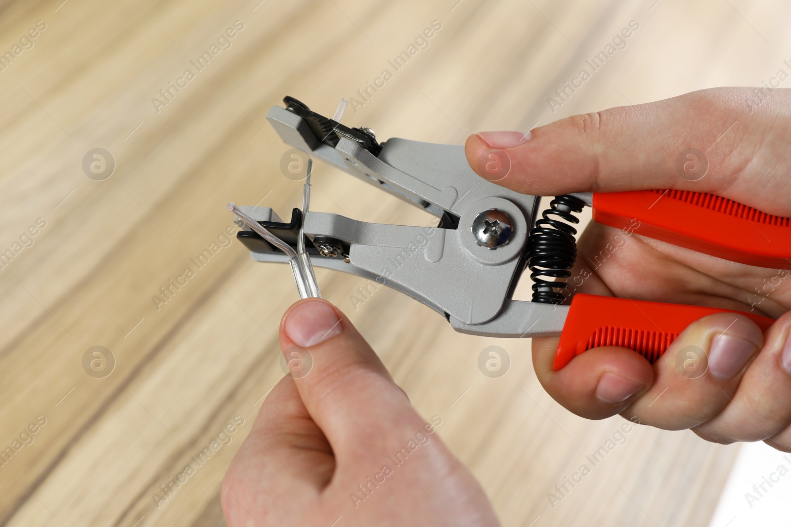 Photo of Professional electrician stripping wiring at wooden table, above view