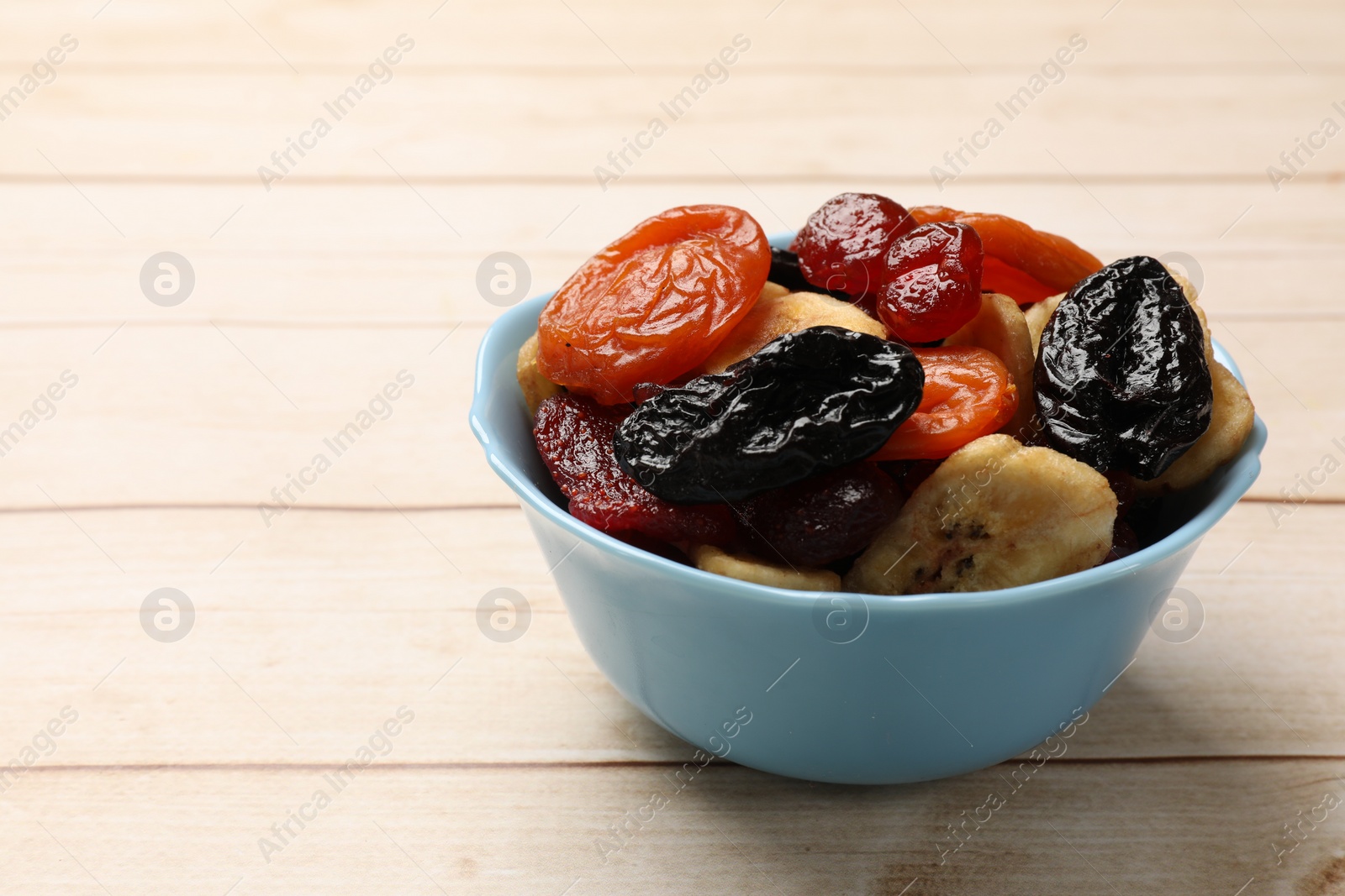 Photo of Mix of delicious dried fruits on white wooden table, closeup. Space for text