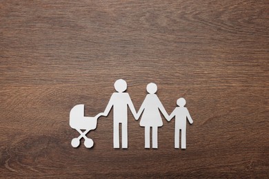 Photo of Paper family cutout on wooden background, top view. Insurance concept