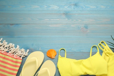 Photo of Beach towel, flip flops and swimsuit on light blue wooden background, flat lay. Space for text