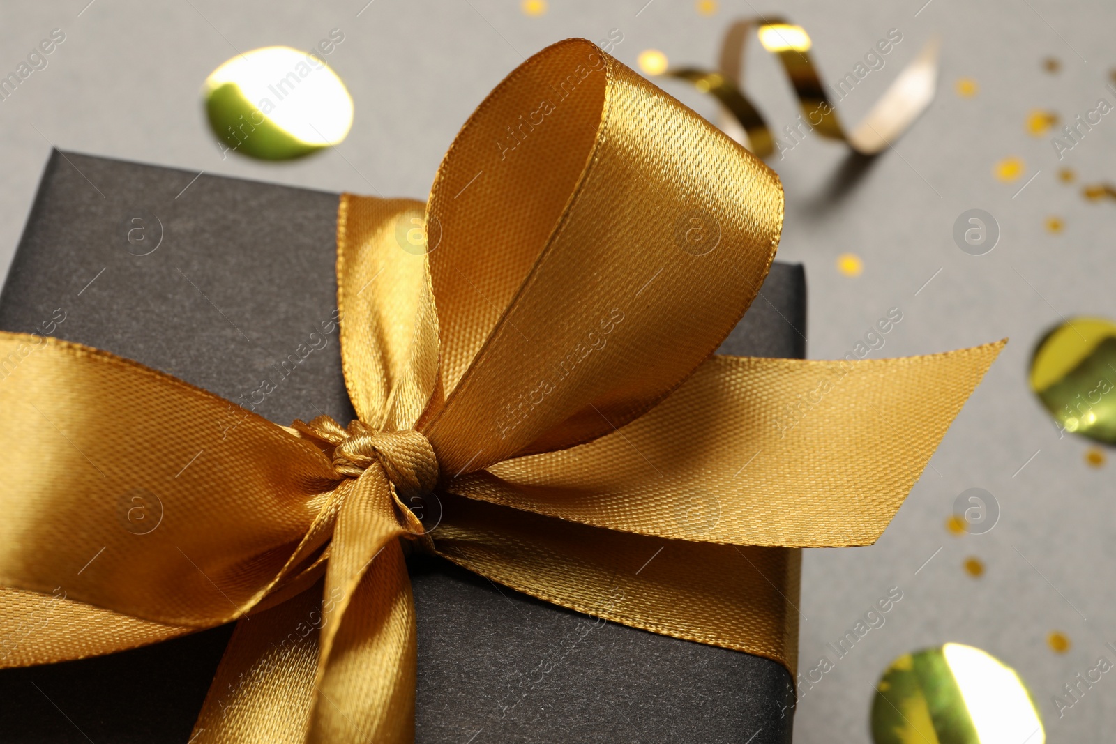 Photo of Black gift box with bow on grey background, closeup