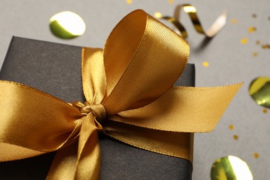 Photo of Black gift box with bow on grey background, closeup