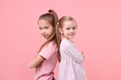 Photo of Portrait of cute little sisters on pink background