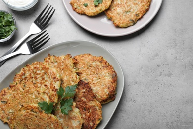 Delicious zucchini fritters served on grey table, flat lay