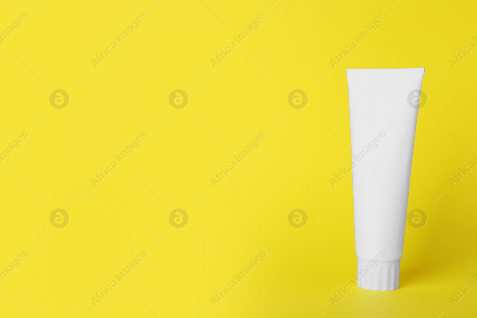 Photo of Blank tube of toothpaste on yellow background. Space for text