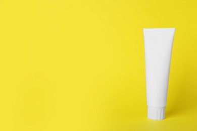 Photo of Blank tube of toothpaste on yellow background. Space for text