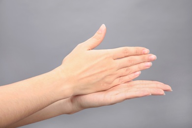 Photo of Woman showing word stop on grey background, closeup. Sign language