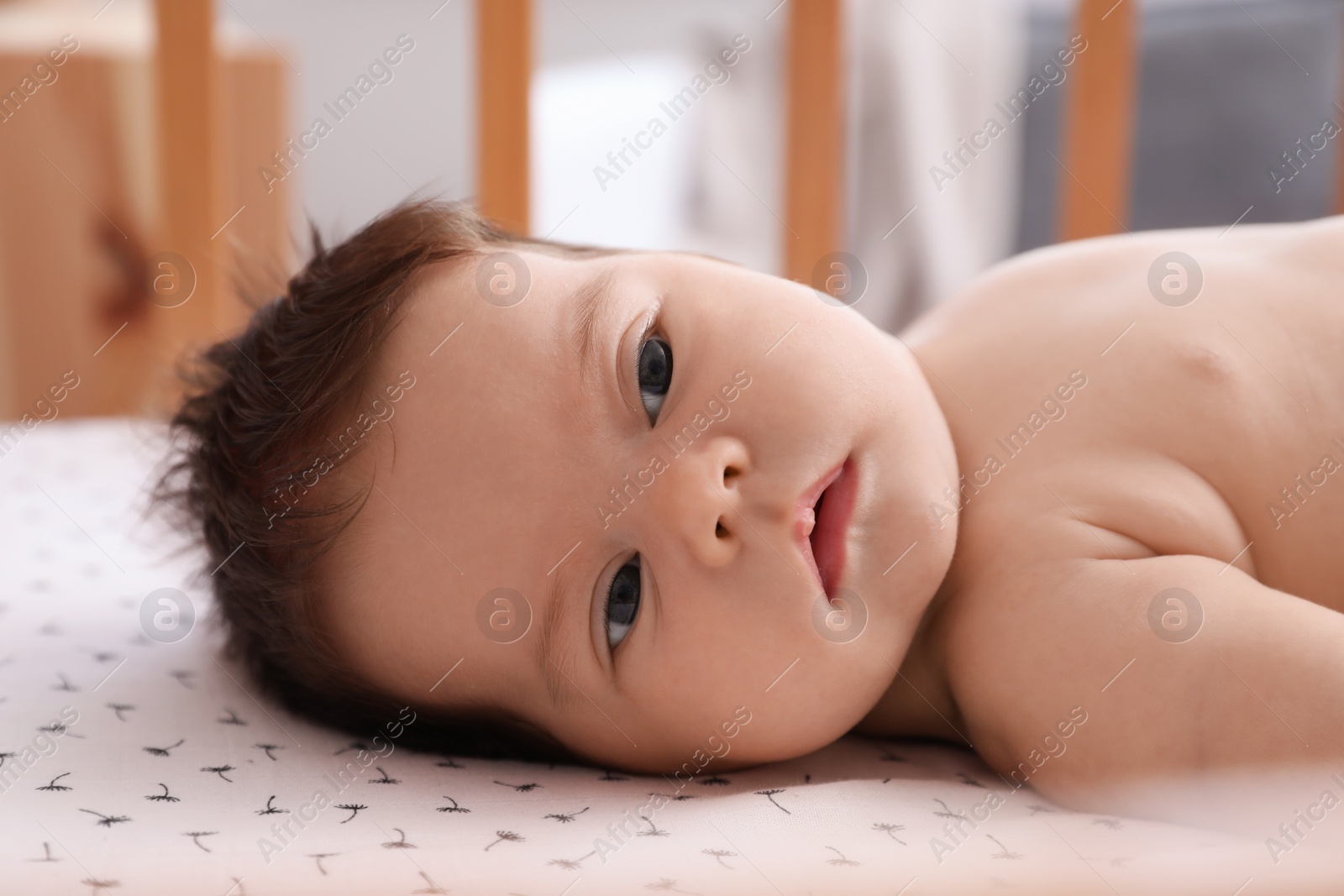 Photo of Cute little baby lying in comfortable crib at home. Bedtime