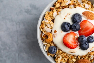 Photo of Tasty granola, yogurt and fresh berries in bowl on light grey table, top view with space for text. Healthy breakfast