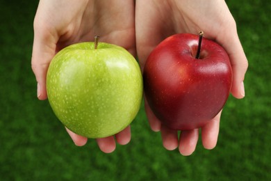 Photo of Woman holding fresh ripe red and green apples outdoors, closeup