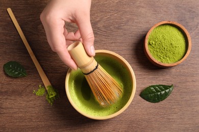 Photo of Woman preparing matcha tea at wooden table, top view